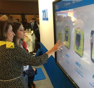 two women touching large touchscreen at tradeshow