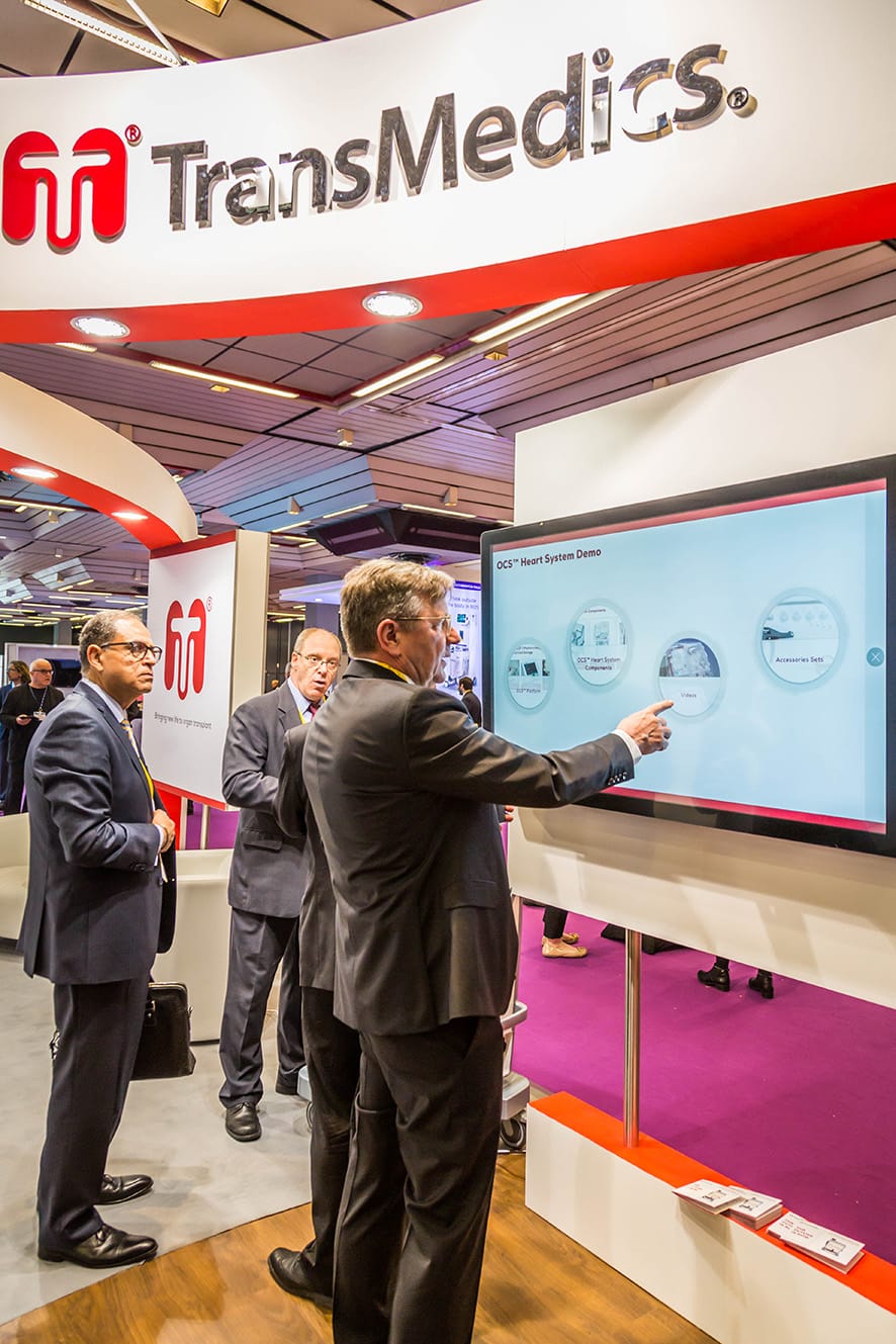 doctors in trade show booth touching large screen