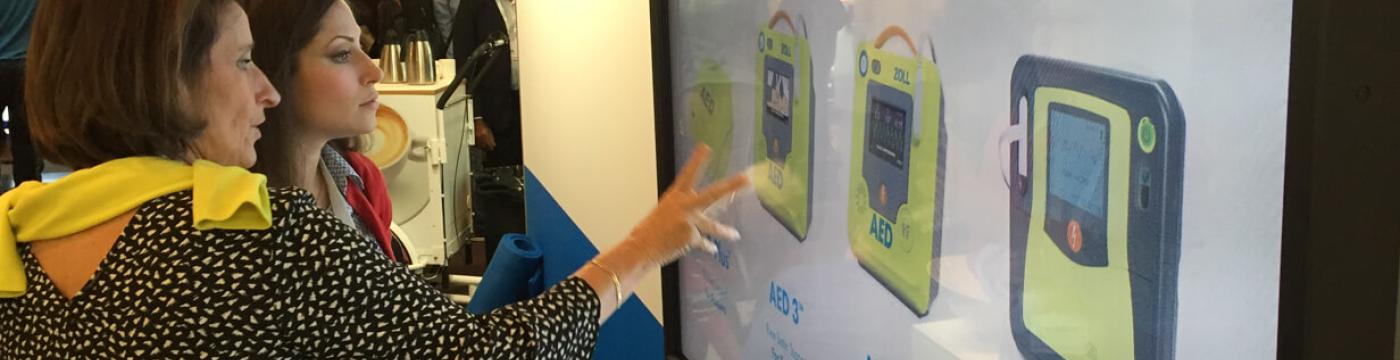 two women touching large touchscreen at tradeshow two women touching large touchscreen at tradeshow