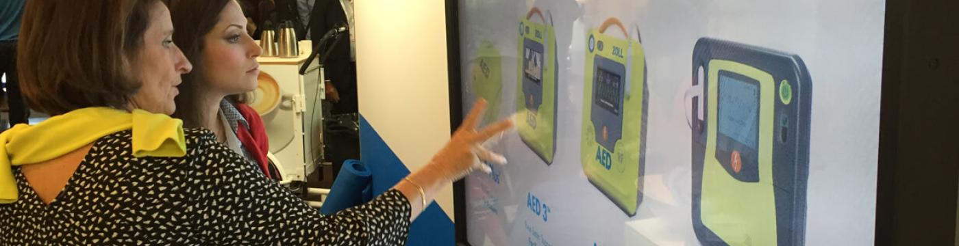 two women touching large touchscreen at tradeshow